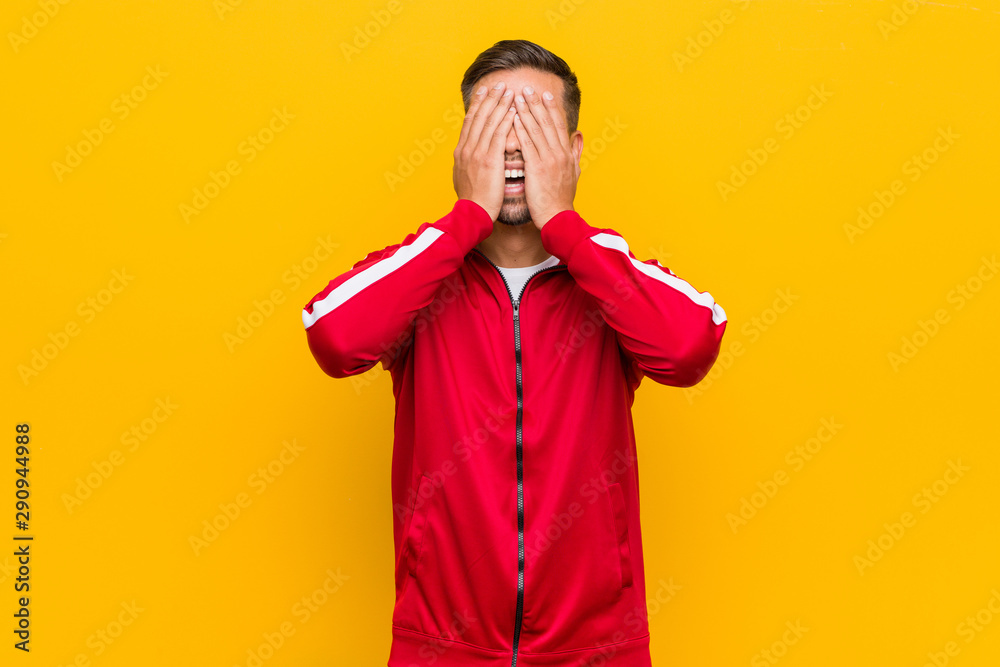Young filipino fitness man covers eyes with hands, smiles broadly waiting for a surprise. Young filipino fitness man covers eyes with hands, smiles broadly waiting for a surprise.