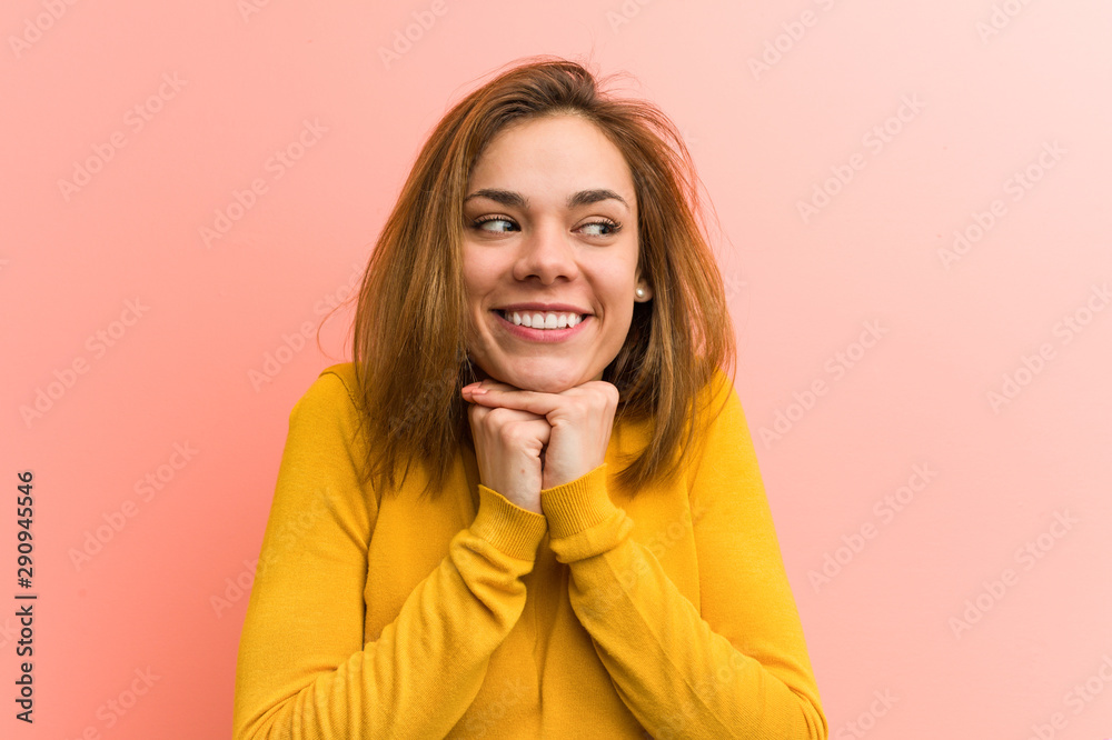 Young pretty young woman keeps hands under chin, is looking happily aside. Young pretty young woman keeps hands under chin, is looking happily aside.