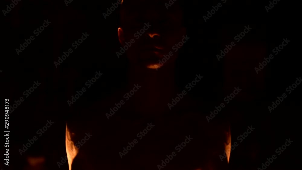 Close-up Slow motion of a young man in black pants in total darkness shows a representation of a rotating burning torch. Meditation in motion. Calm and unwavering. Work with fire. Low key Close-up Slow motion of a young man in black pants in total darkness shows a representation of a rotating burning torch. Meditation in motion. Calm and unwavering. Work with fire. Low key