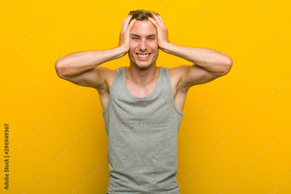 Young caucasian sport man laughs joyfully keeping hands on head. Happiness concept. Young caucasian sport man laughs joyfully keeping hands on head. Happiness concept.