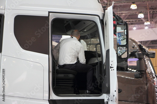 Businessman in white shirt sitting in the cab of a new truck, the choice of cargo transport for logistics company