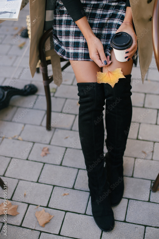 Woman in trench with coffee and autumn leaf in her hands. Woman in trench with coffee and autumn leaf in her hands.