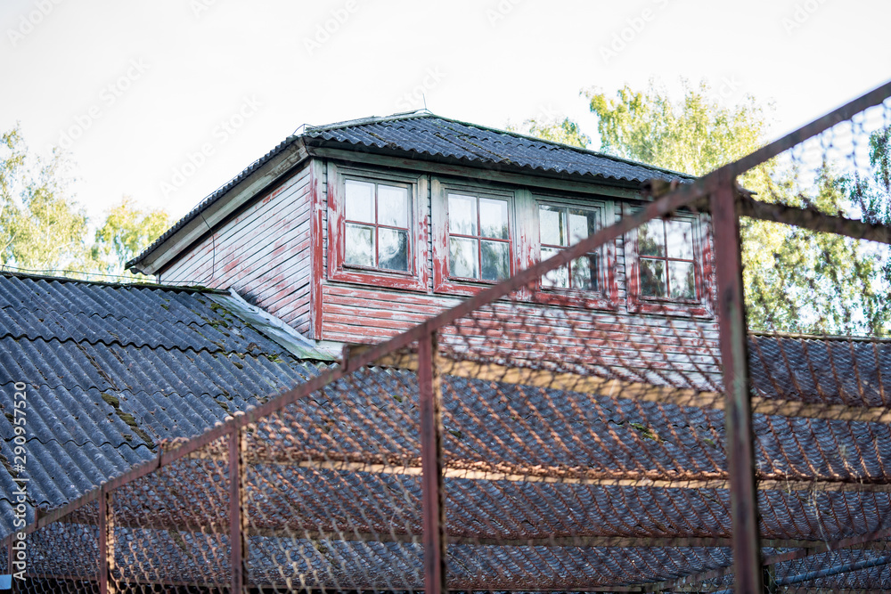 Old building behind high metallic fence. Looks like prison or forced labor camp with watchtower. Old building behind high metallic fence. Looks like prison or forced labor camp with watchtower.