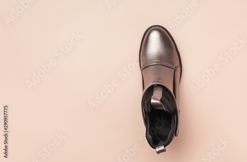 Silver female leather ankle boots on a pink background.