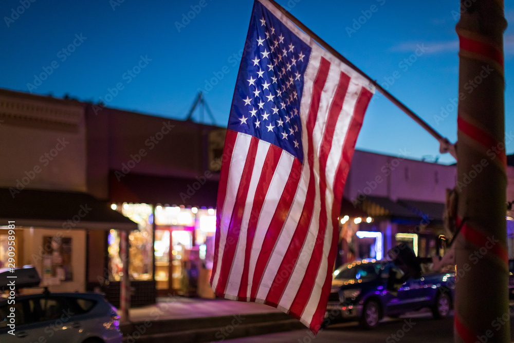 Close up night shot of a waving american flag hanging from a shop in a small californian backcountry town