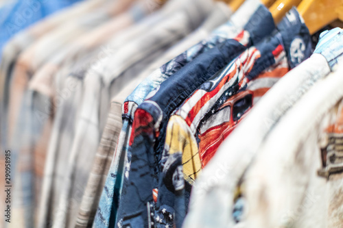 Close up of a row of colorful jeans shirts on hangers