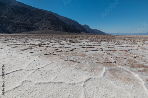 Low angle view of the rough surface on the salt lake of Badwater Basin, under a blue sky with no clouds photo