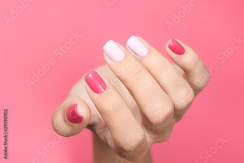 Photography Closeup view of single beautiful white hand of caucasian adult woman with trendy asymmetric two colours bright manicure isolated on pink background