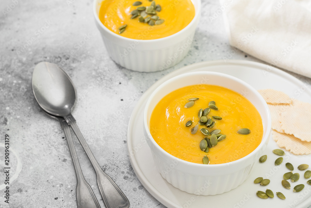 Autumn pumpkin cream soup with seeds. Light grey background Autumn pumpkin cream soup with seeds. Light grey background