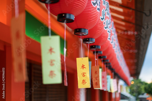 Close up of a row of red votive lantern with colored kanji writings dangling in a japanese temple