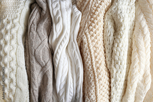Bunch of knitted warm pastel color sweaters with different vertical knitting patterns hanging in bunch, clearly visible texture. Stylish fall / winter season knitwear clothing. Close up, copy space. photo