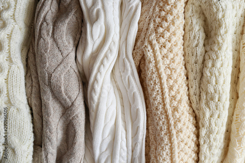 Bunch of knitted warm pastel color sweaters with different vertical knitting patterns hanging in bunch, clearly visible texture. Stylish fall / winter season knitwear clothing. Close up, copy space. photo