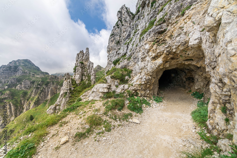 Entrance of a gallery carved into the rock in a mountain trail in northern Italy