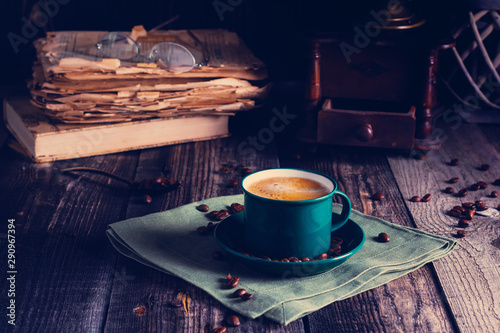 Cafe background with a green cup of espresso coffee standing on a linen napkin with a retro coffee grinder old book. Retro style Nashville. Tonted image. photo