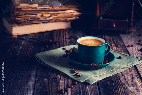 Cafe background with a green cup of espresso coffee standing on a linen napkin with a retro coffee grinder old book. Retro style Nashville. Tonted image. photo