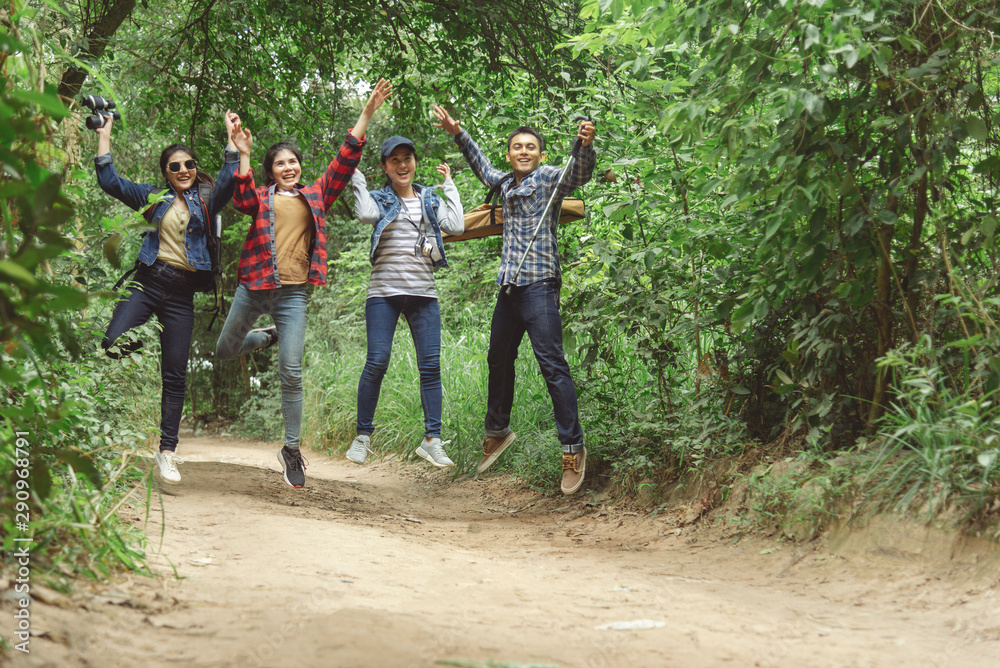 Fototapeta premium Happy smiling friends with musical instruments jumping in the forest outdoors