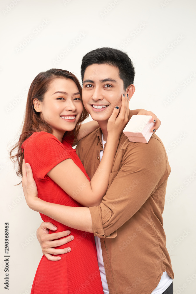 Young couple hugging with wrapped present. woman embracing man and holding present with ribbon Young couple hugging with wrapped present. woman embracing man and holding present with ribbon