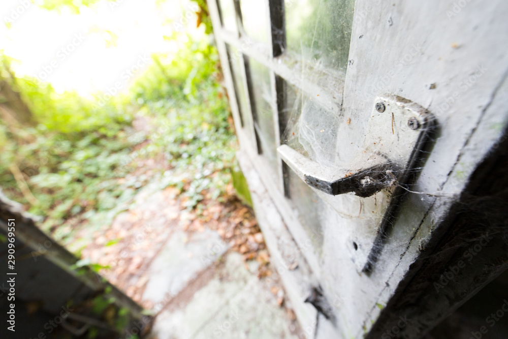 Close up of the door of an old and abandoned building, with the handle covered with spiderwebs Close up of the door of an old and abandoned building, with the handle covered with spiderwebs