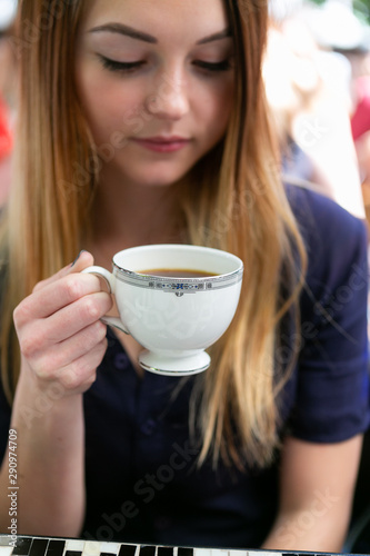 Cute girl sipping coffee out of a vintage tea cup in cafe