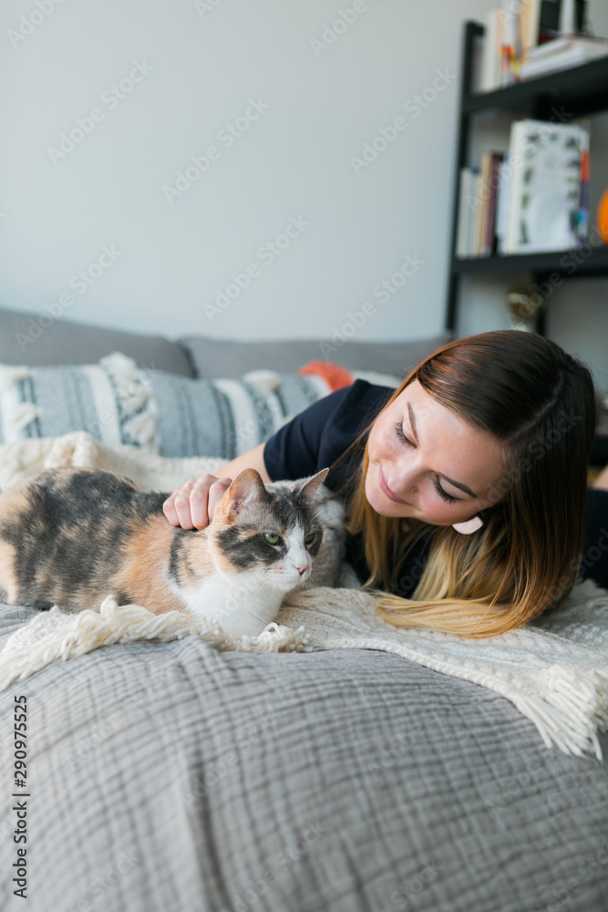 Cute girl cuddling with calico cat on bed in apartment, copy space, sweet Cute girl cuddling with calico cat on bed in apartment, copy space, sweet