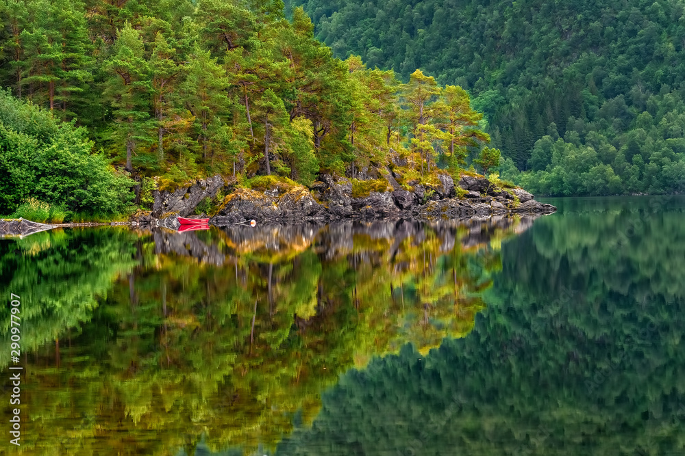 Reflections in the calm water of the Norwegian crystal clear lake with a rocky bottom in a small town Skodje, Norway. Reflections in the calm water of the Norwegian crystal clear lake with a rocky bottom in a small town Skodje, Norway.