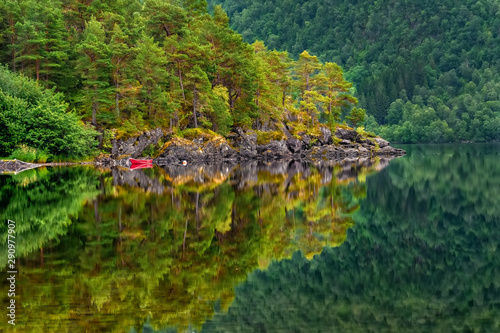 Reflections in the calm water of the Norwegian crystal clear lake with a rocky bottom in a small town Skodje  Norway.