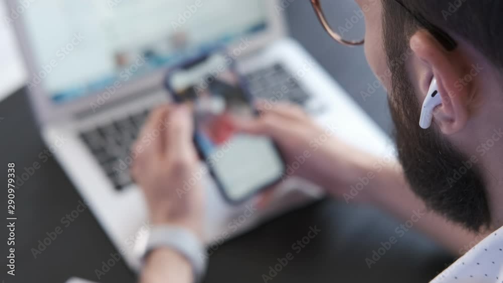Man looks at the photos in the application. Male office worker browsing social networks site. Handsome man using smartphone scrolling pictures, photos in application. Screen is blurred. Close up