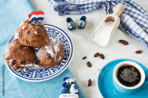 Oil dumplings (oliebollen) on blue plate, with wooden shoes, sugar spoon and coffee. Traditional treat on New Years Eve in The Netherlands