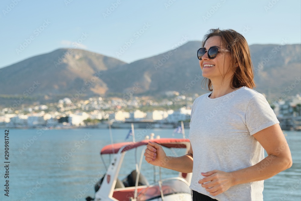 Smiling mature woman running jogging at seaside promenade