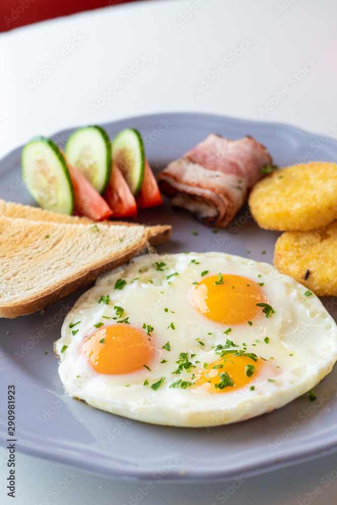 Close up of british breakfast with fried egg, wheat crunchy toasts, potato hash browns, bacon and salad Close up of british breakfast with fried egg, wheat crunchy toasts, potato hash browns, bacon and salad