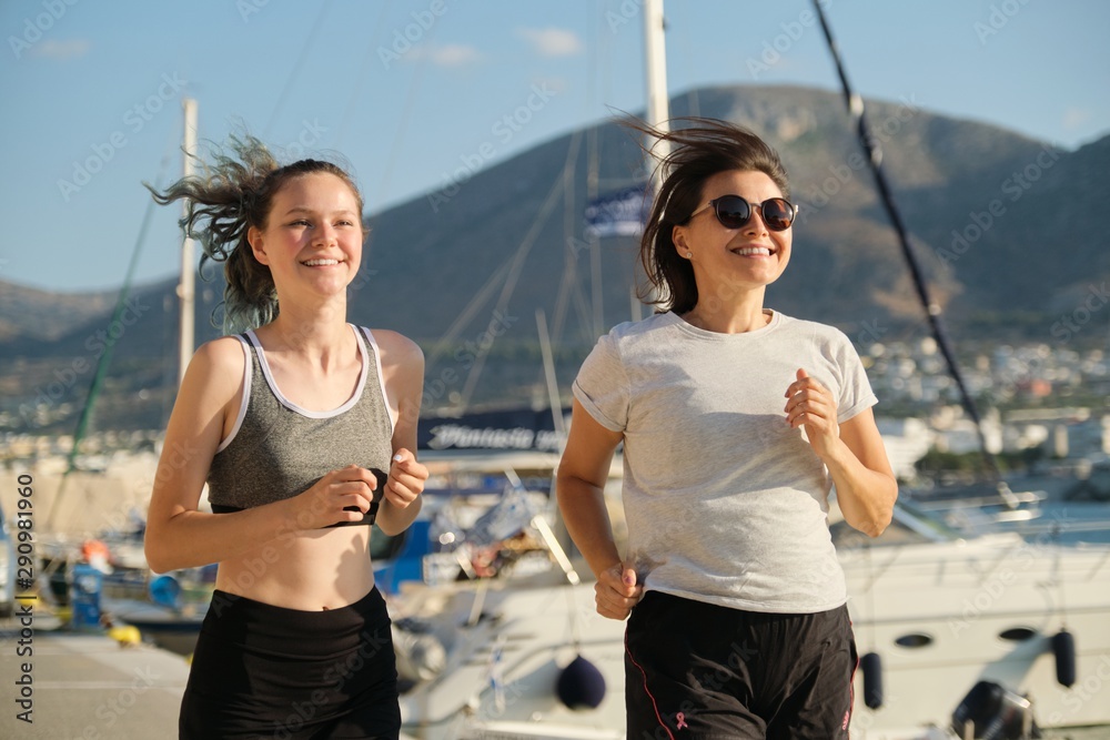 Mother and daughter jogging running at seaside promenade together