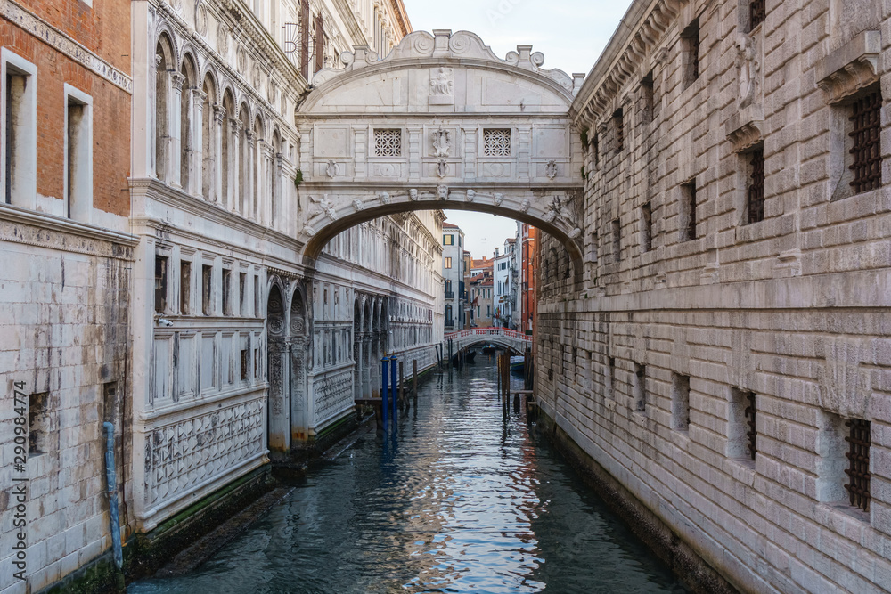 Boats on narrow canal between colorful historic houses in Venice.