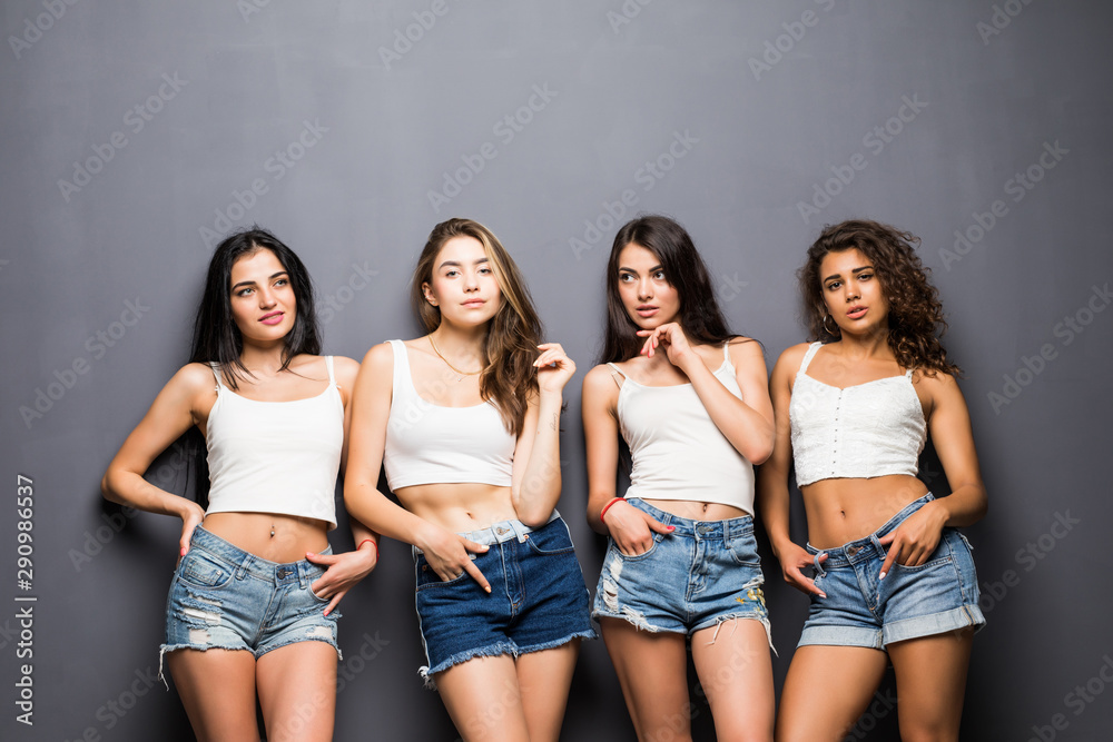 Four happy women friends standing over gray background Four happy women friends standing over gray background