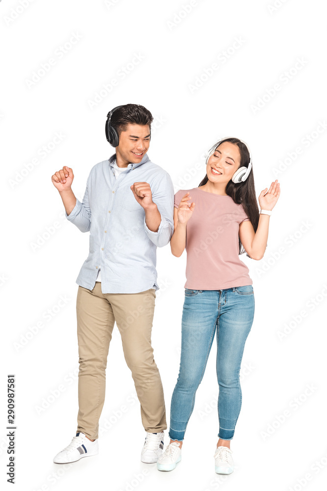 happy asian couple looking at each other while listening music in headphones and dancing on white background happy asian couple looking at each other while listening music in headphones and dancing on white background