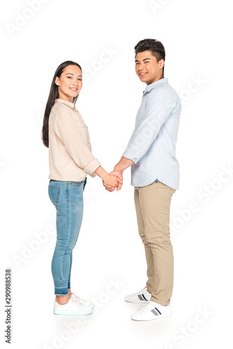 happy asian couple holding hands and smiling at camera on white background