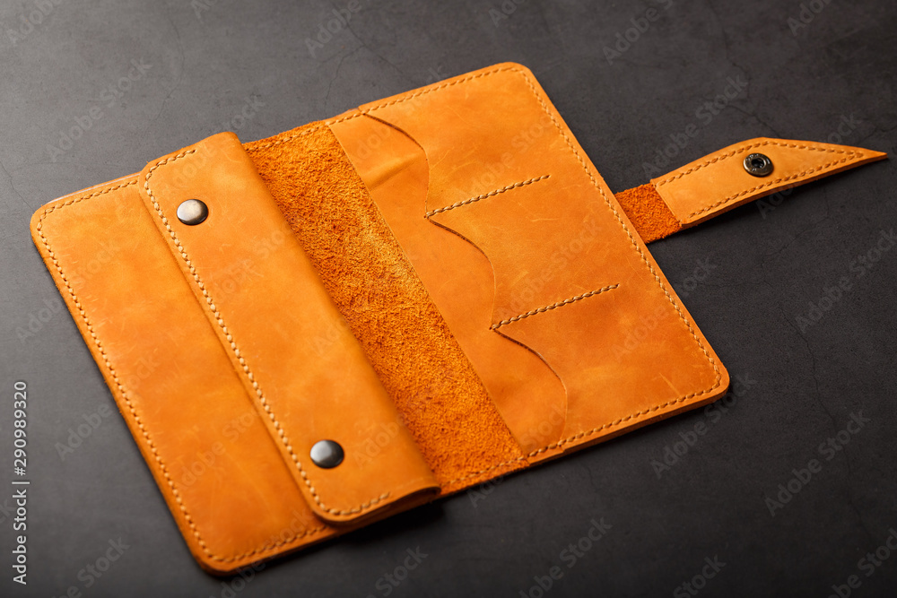 Wallet made of genuine brown nubuck leather on a dark background. Handmade leather items Wallet made of genuine brown nubuck leather on a dark background. Handmade leather items