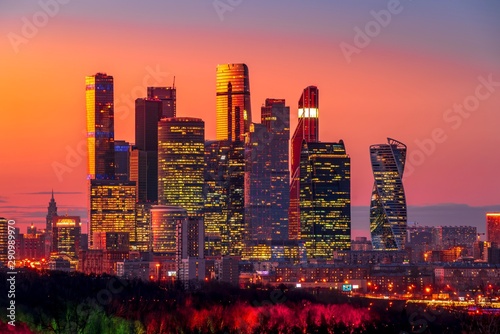 Wonderful modern city view with the orange sky and illuminated skyscrapers after sunset