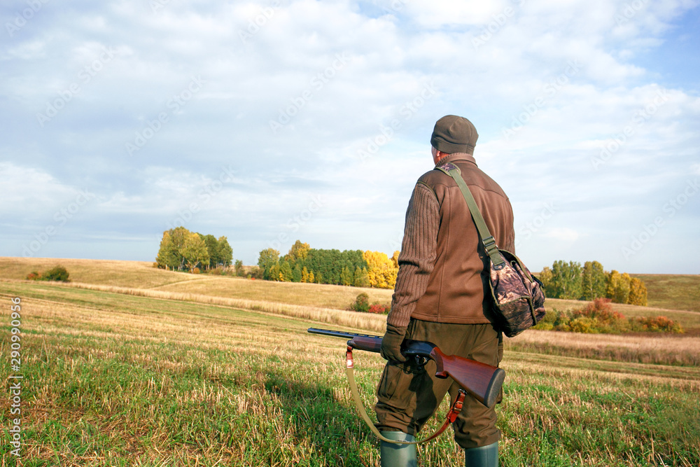 A hunter with a hunting gun and hunting form to hunt in an autumn forest. Hunter with rifle. A hunter with a hunting gun and hunting form to hunt in an autumn forest. Hunter with rifle.