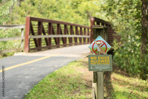 A sign prohibiting dogs on a pedestrian trail warns people of a fine