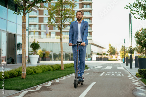 Young businessman in a suit riding an electric scooter