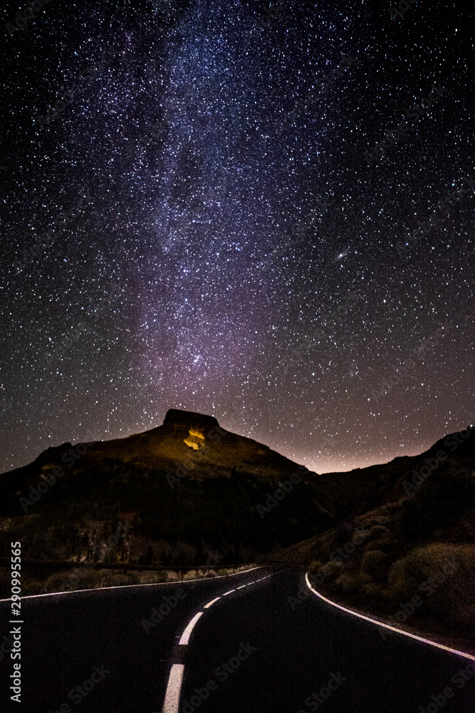 Concept of travel in amazing scenic places with long asphalt road by night and milky way stars on. the black sky