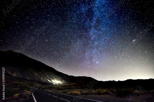 Concept of travel in amazing scenic places with long asphalt road by night and milky way stars on. the black sky