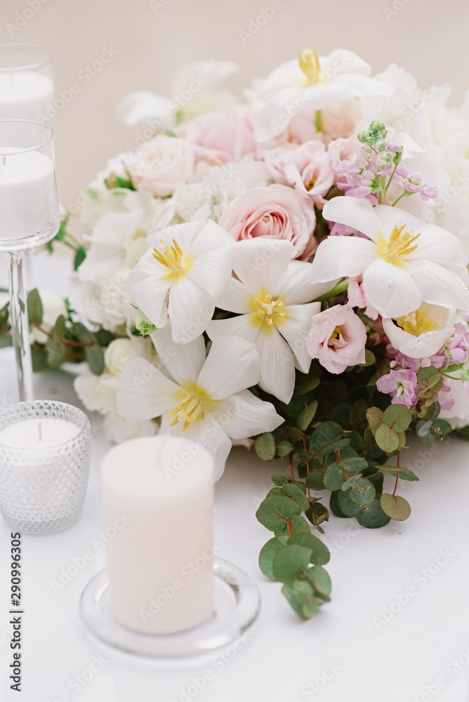 White candles and bouquet from an assortment of fresh and beautiful flowers decorate the festive table