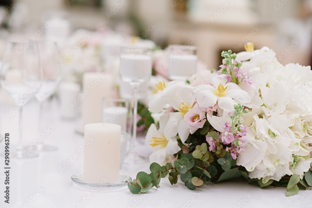 Luxury decoration of the wedding table with white candles and flowers in light shades