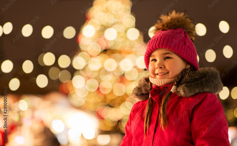 holidays, childhood and people concept - happy little girl at christmas market in winter evening holidays, childhood and people concept - happy little girl at christmas market in winter evening
