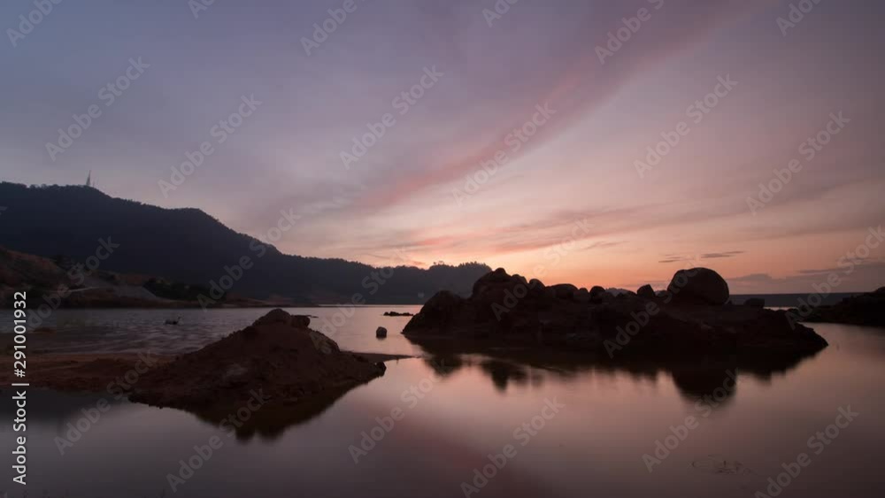 Timelapse silhouette sunset reflection at Mengkuang dam. Beautiful red cloud over stone and hill. Timelapse silhouette sunset reflection at Mengkuang dam. Beautiful red cloud over stone and hill.