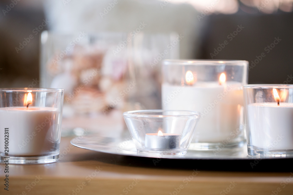decoration, hygge and cosiness concept - burning white fragrance candles on tray on table