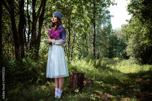 Young brunette woman walks in a summer forest park wearing stylish casual clothes, fashion style portrait