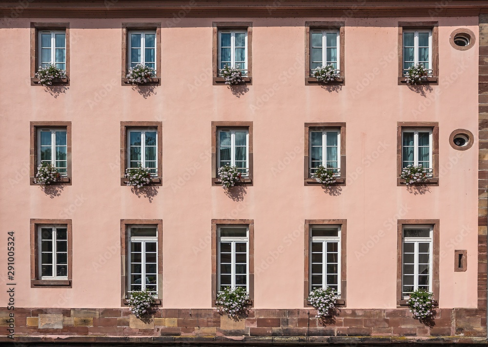 Pink facade of a building with windows and flowers in pots in the historic district 