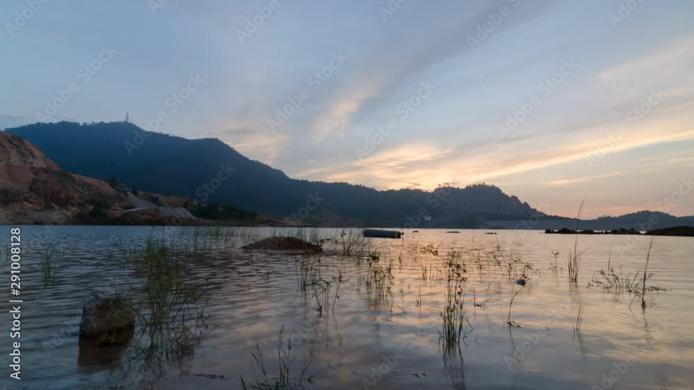 Timelapse over Bukit Mertajam Hill view from Mengkuang Dam with plant grow in the water nearby rock. Timelapse over Bukit Mertajam Hill view from Mengkuang Dam with plant grow in the water nearby rock.